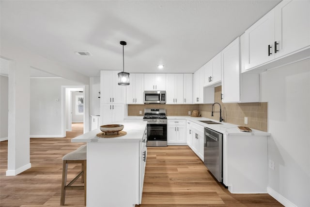 409 24th Ave N, Texas City, TX 77590 - kitchen featuring appliances with stainless steel finishes, backsplash, a kitchen island, light wood-style flooring, and light countertops