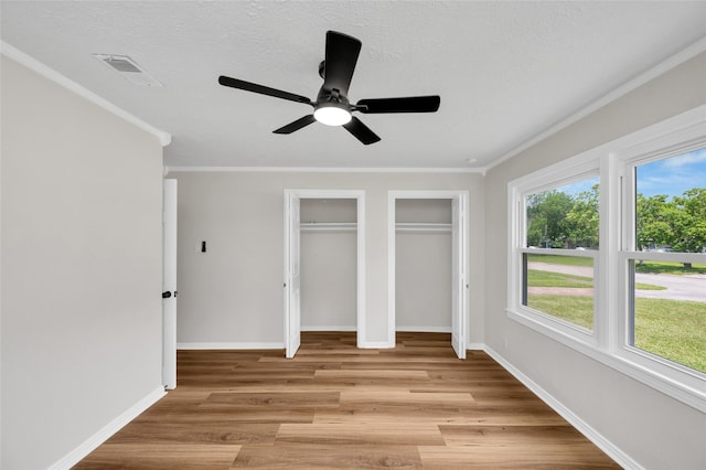 409 24th Ave N, Texas City, TX 77590 - unfurnished bedroom with two closets, light wood-style flooring, crown molding, and ceiling fan