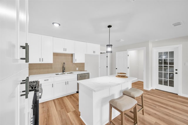 409 24th Ave N, Texas City, TX 77590 - kitchen featuring appliances with stainless steel finishes, a kitchen breakfast bar, light wood finished floors, decorative backsplash, and light stone countertops