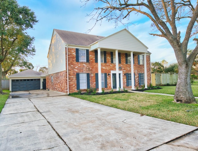 greek revival inspired property featuring fence, a detached garage, brick siding, and a front yard