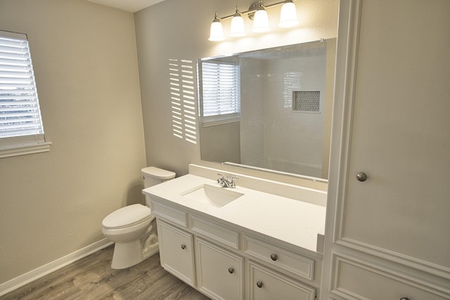 bathroom featuring baseboards, wood finished floors, a healthy amount of sunlight, and toilet