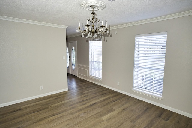 unfurnished room featuring dark wood-type flooring, crown molding, a notable chandelier, and a wealth of natural light