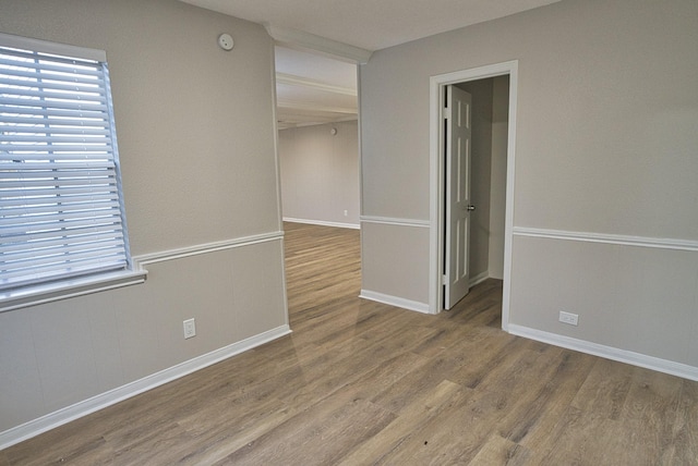 empty room featuring a healthy amount of sunlight, baseboards, and wood finished floors