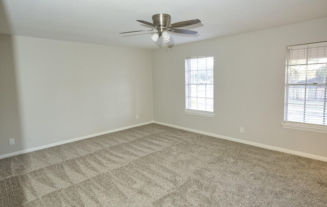 carpeted spare room with a ceiling fan and baseboards