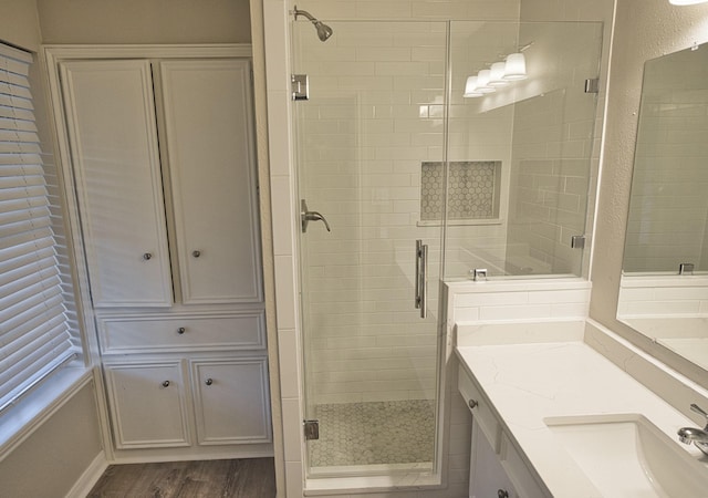 bathroom with vanity, wood finished floors, and a shower stall