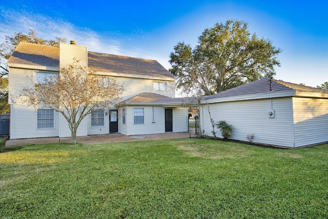 back of property featuring a patio, an outbuilding, a yard, and a chimney