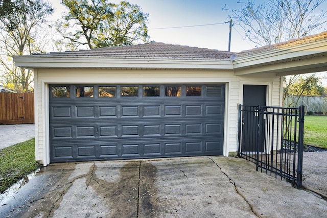 garage featuring fence and driveway