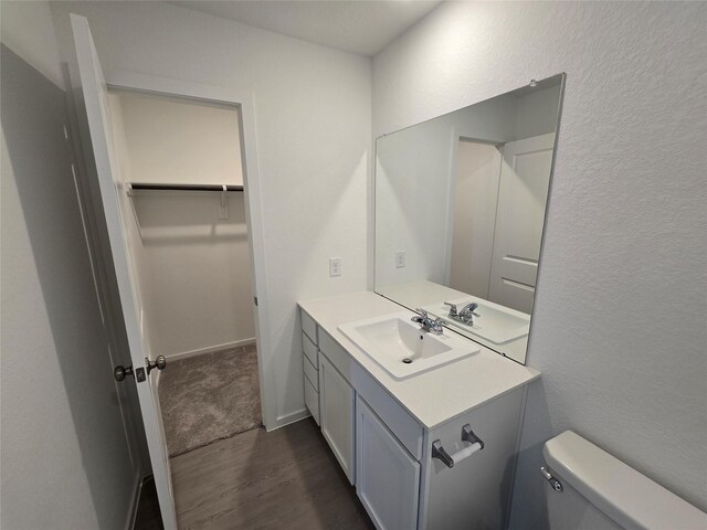 10819 Red Orchid Dr, Houston, TX 77016 - bathroom with wood finished floors, vanity, toilet, and a textured wall