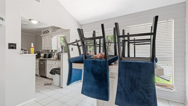 interior space featuring baseboards, vaulted ceiling, and light tile patterned floors