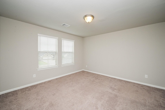 spare room featuring carpet floors, baseboards, and visible vents