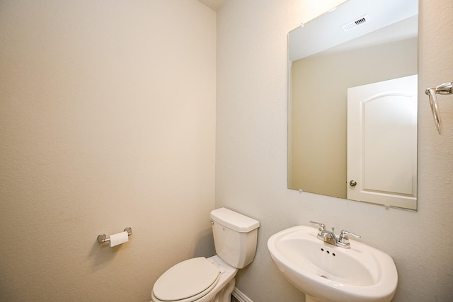 half bathroom featuring visible vents, a sink, and toilet
