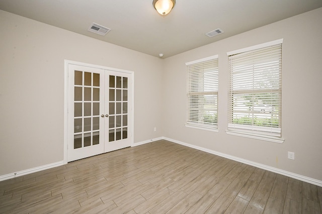 spare room featuring baseboards, visible vents, and french doors