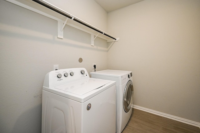 washroom with washer and dryer, laundry area, baseboards, and wood finished floors