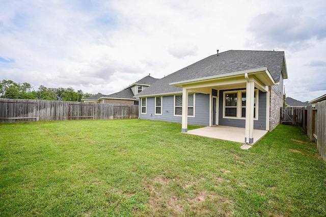 rear view of property with roof with shingles, a patio, a lawn, and a fenced backyard