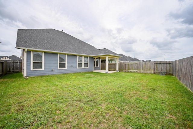back of property featuring a lawn, a patio, a fenced backyard, and roof with shingles