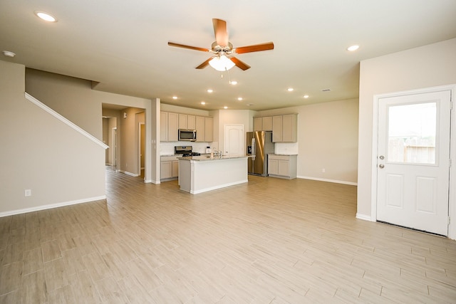 unfurnished living room with baseboards, light wood-style floors, ceiling fan, recessed lighting, and a sink