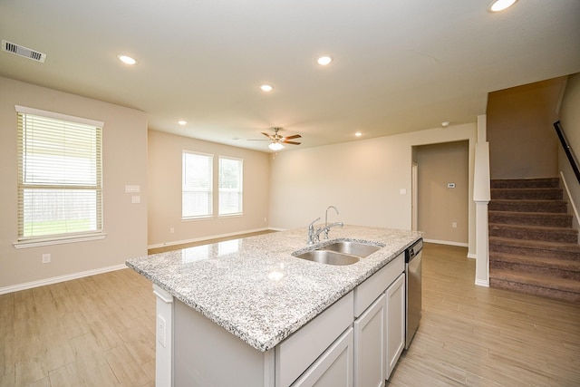 kitchen featuring stainless steel dishwasher, visible vents, a sink, and light wood-style flooring