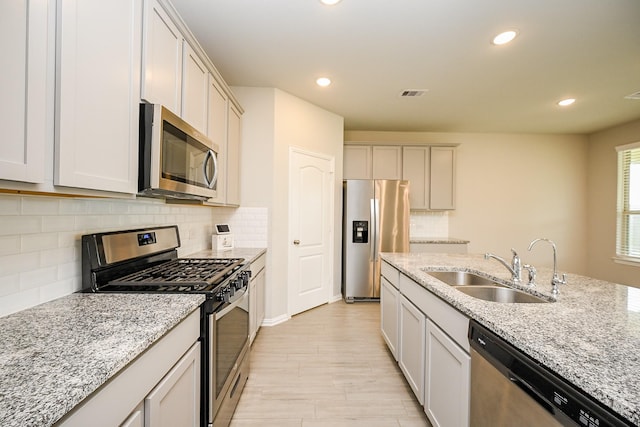 kitchen featuring visible vents, recessed lighting, light stone counters, a sink, and appliances with stainless steel finishes
