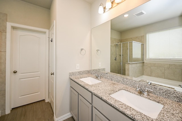 full bath featuring a sink, a shower stall, wood finished floors, and visible vents