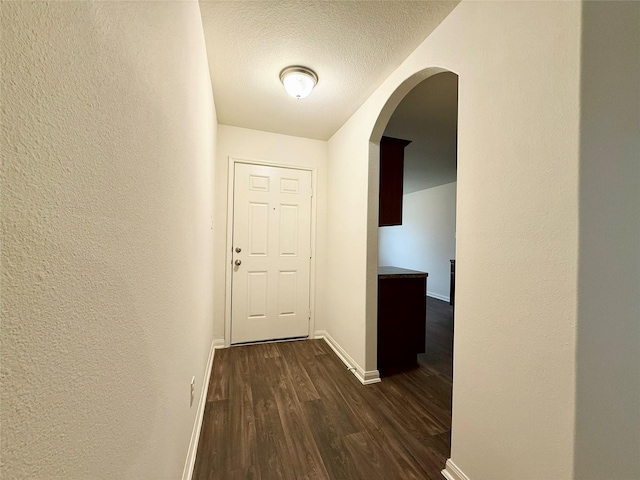 2093 Saras Way, Brookshire, TX 77423 - corridor with a textured ceiling, arched walkways, dark wood finished floors, baseboards, and a textured wall