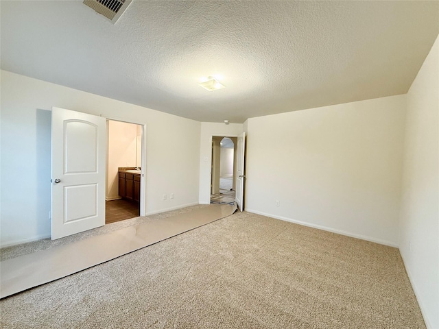 2093 Saras Way, Brookshire, TX 77423 - unfurnished bedroom featuring connected bathroom, a textured ceiling, carpet, baseboards, and visible vents