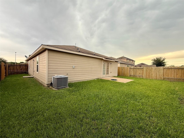 2093 Saras Way, Brookshire, TX 77423 - back of property at dusk with a lawn, central AC unit, a fenced backyard, and french doors