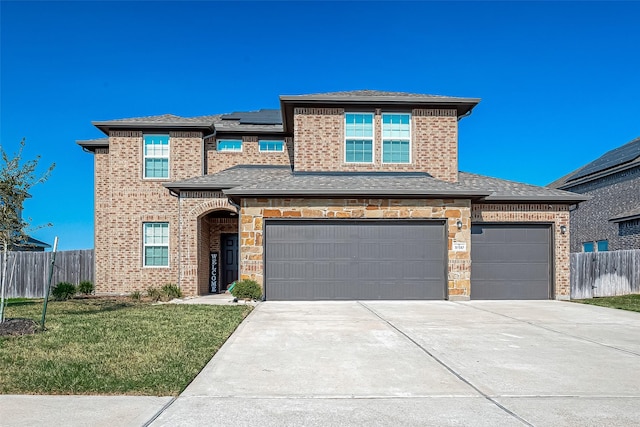 traditional home featuring fence, a front lawn, roof mounted solar panels, and driveway