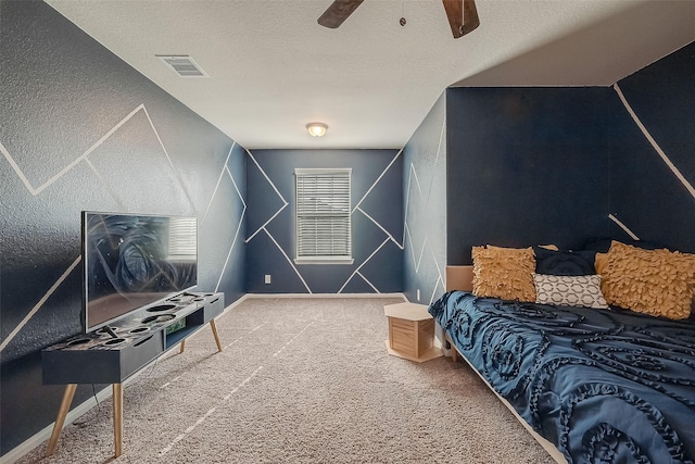 carpeted bedroom with ceiling fan, a textured ceiling, visible vents, baseboards, and a textured wall