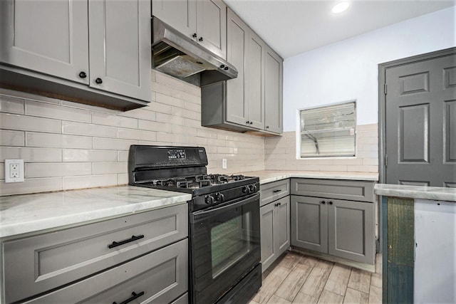 kitchen featuring black gas range, recessed lighting, under cabinet range hood, light stone counters, and gray cabinetry