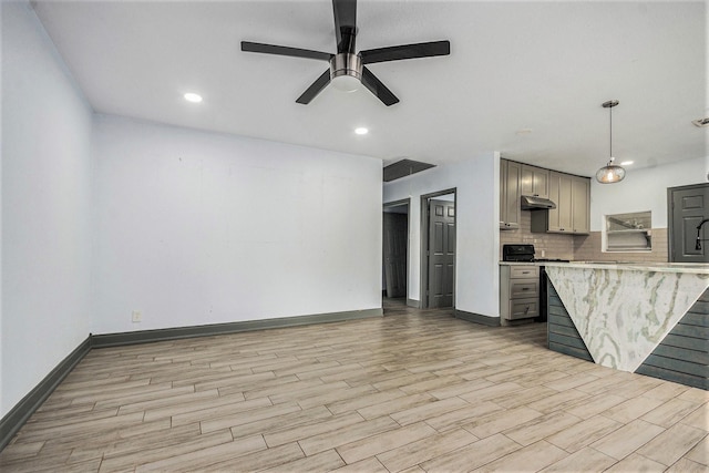 kitchen with gray cabinetry, tasteful backsplash, under cabinet range hood, and light wood finished floors