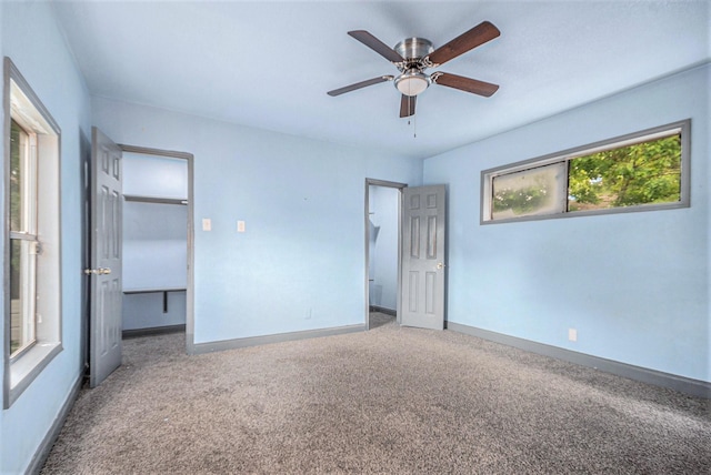 unfurnished bedroom featuring baseboards, ceiling fan, carpet, and a spacious closet
