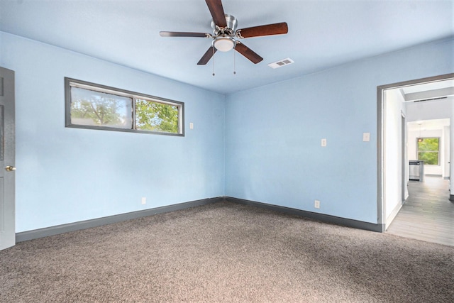 empty room featuring visible vents, carpet flooring, baseboards, and a ceiling fan