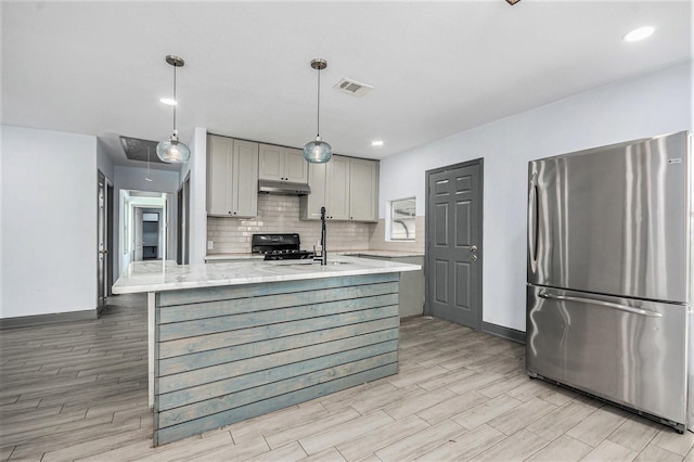 kitchen featuring gray cabinets, visible vents, freestanding refrigerator, light wood finished floors, and under cabinet range hood
