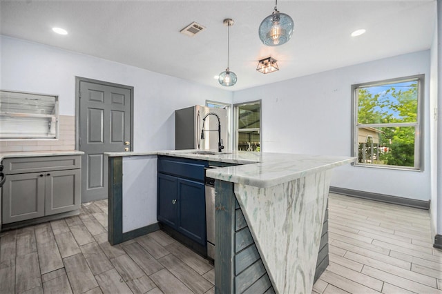 kitchen with a sink, a center island with sink, wood finish floors, and visible vents