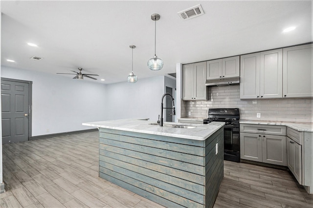 kitchen featuring gray cabinetry, a sink, visible vents, and black gas stove