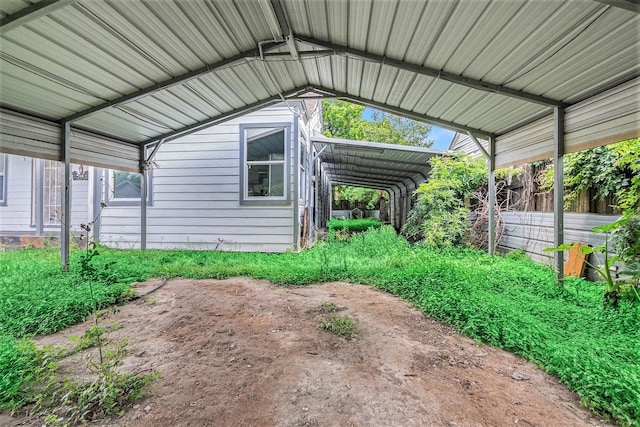 view of vehicle parking with fence and a carport