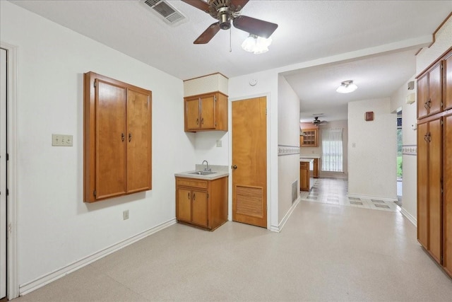 kitchen with ceiling fan, visible vents, brown cabinetry, and baseboards