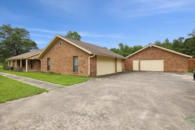 view of front of property with brick siding, a front yard, and a detached garage