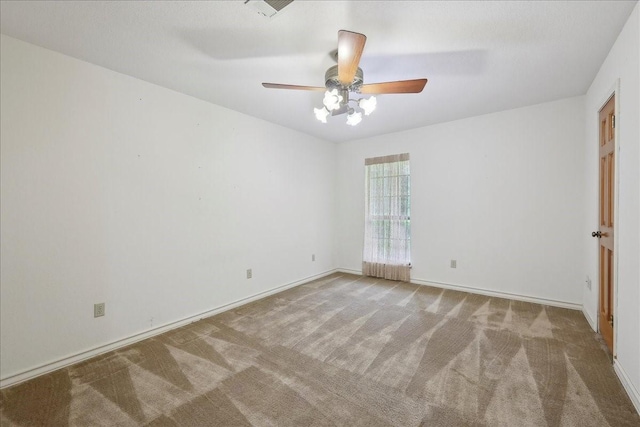 spare room with baseboards, ceiling fan, and carpet