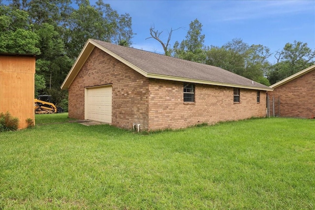 view of home's exterior with a detached garage, a lawn, driveway, and brick siding