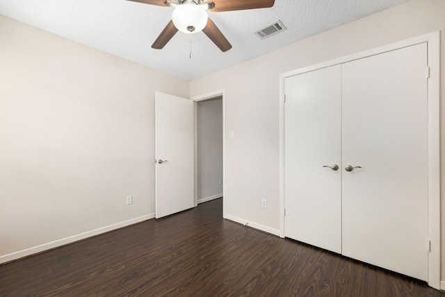 unfurnished bedroom featuring baseboards, dark wood-style floors, visible vents, and a closet