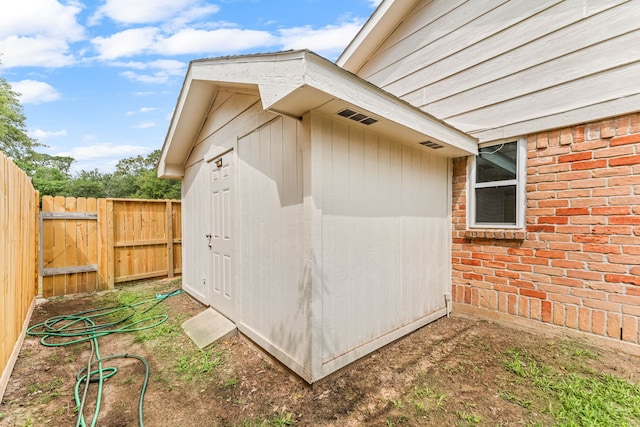 view of side of property with an outbuilding, a storage unit, fence, and a gate