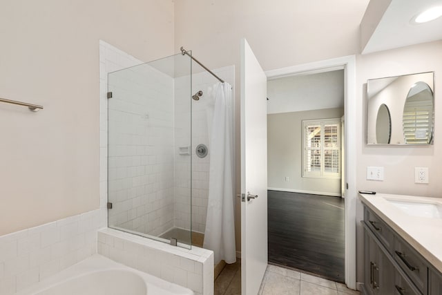 bathroom with vanity, tile patterned floors, baseboards, a bath, and a tile shower