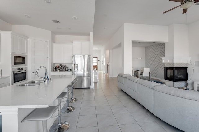 kitchen with stainless steel appliances, a sink, open floor plan, a breakfast bar, and light countertops