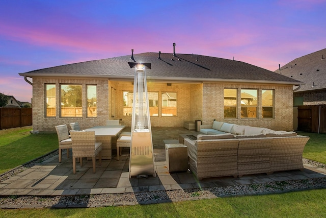 back of house at dusk with an outdoor living space, brick siding, a patio area, roof with shingles, and outdoor dining space