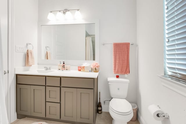 bathroom with toilet, vanity, baseboards, and tile patterned floors