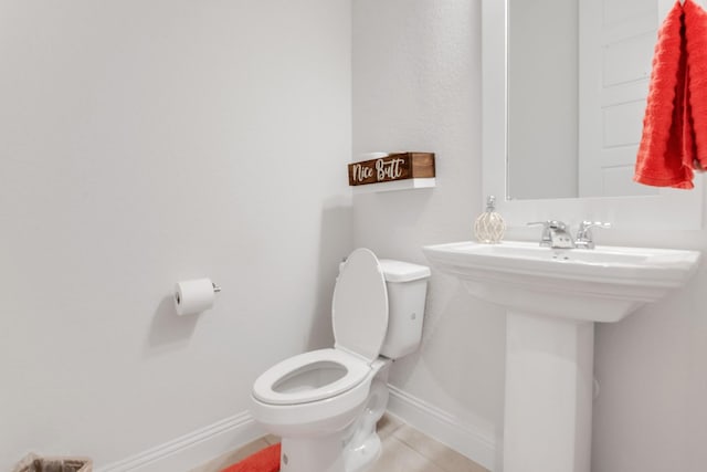 half bathroom featuring toilet, tile patterned floors, and baseboards