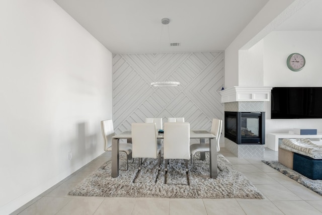 tiled dining room featuring a fireplace and an accent wall