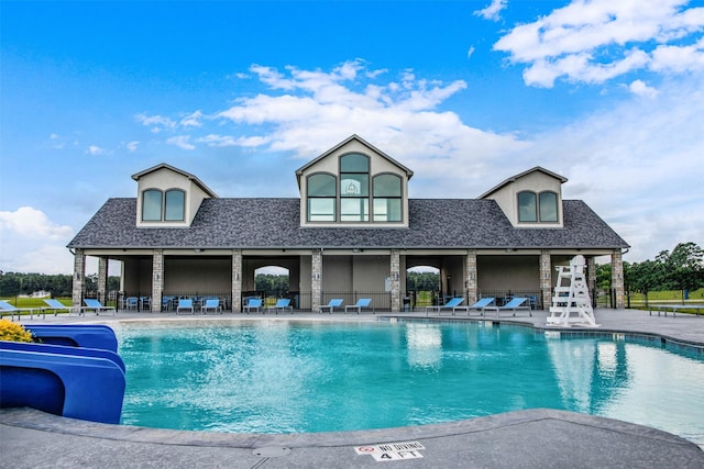 community pool with a patio and a water slide
