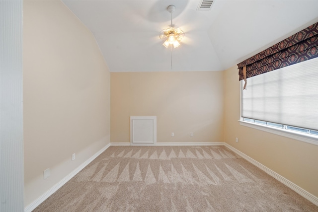 spare room featuring ceiling fan, visible vents, baseboards, lofted ceiling, and carpet